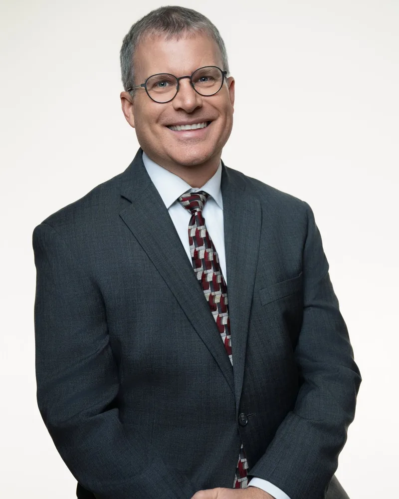 Dean Houdeshell, founder of Innovative Coaching Strategies, smiling in a dark suit and patterned tie